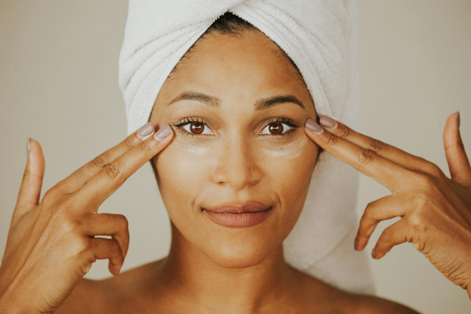 Woman applying moisturiser before concealer for smooth under eyes without creasing